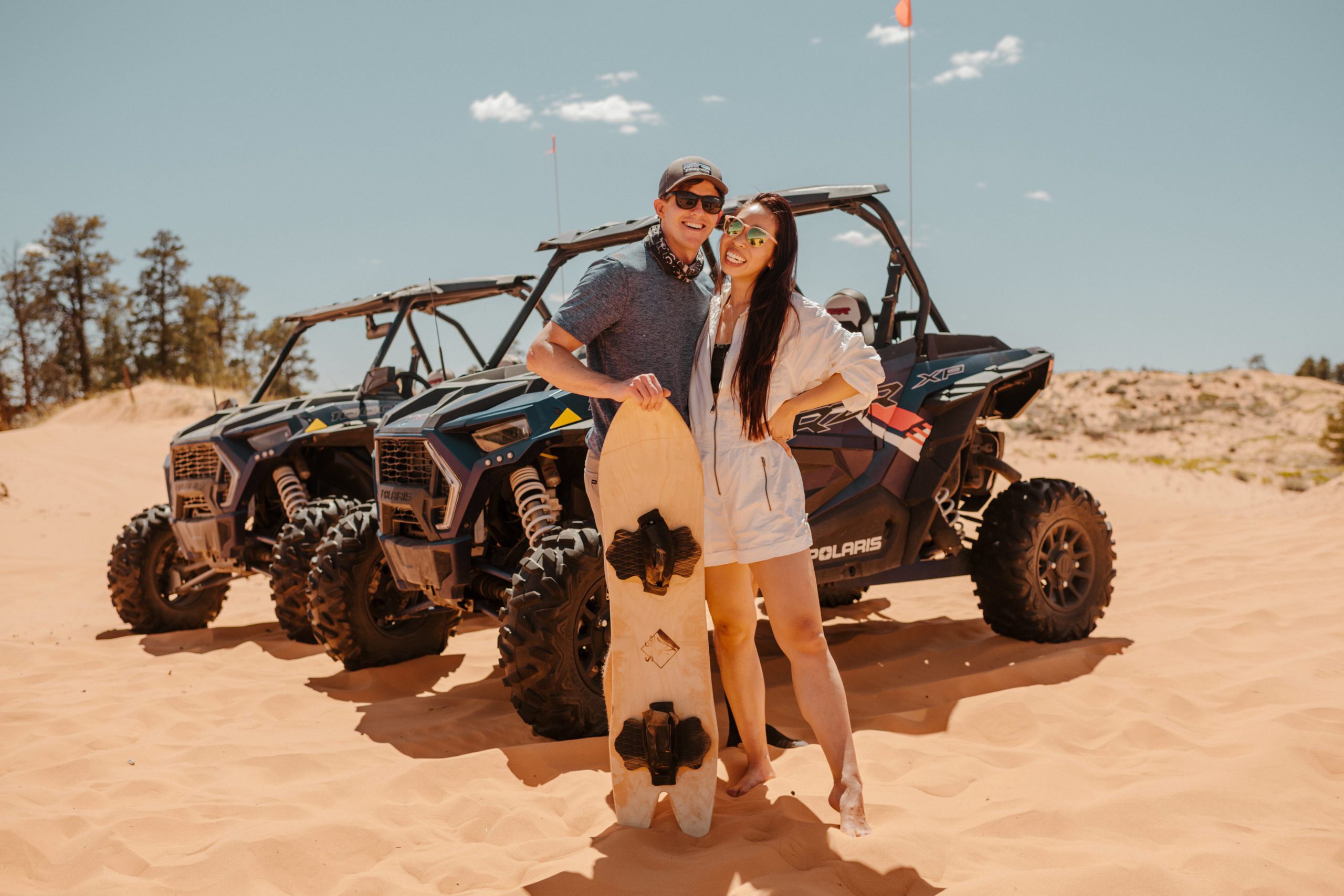 bride and groom standing in front of an atv with a sandboard in southern utah as they celebrate their wedding weekend